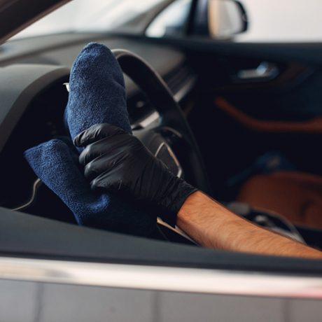 Man in a garage. Worker washing a car.